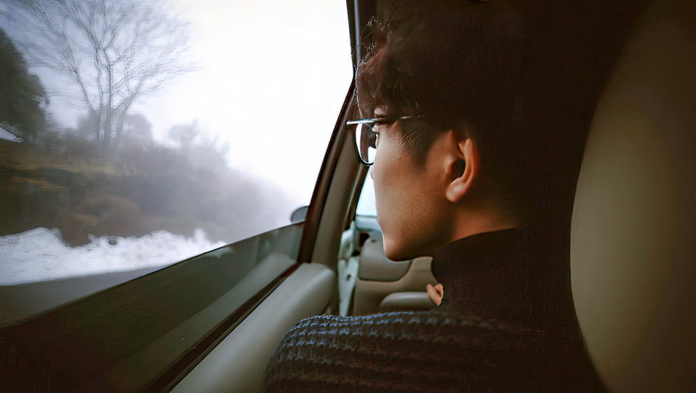 A person staring out of the window of a car.