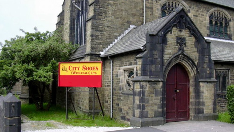 An old church with a sign outside reading "City Shoes Wholesale Ltd".